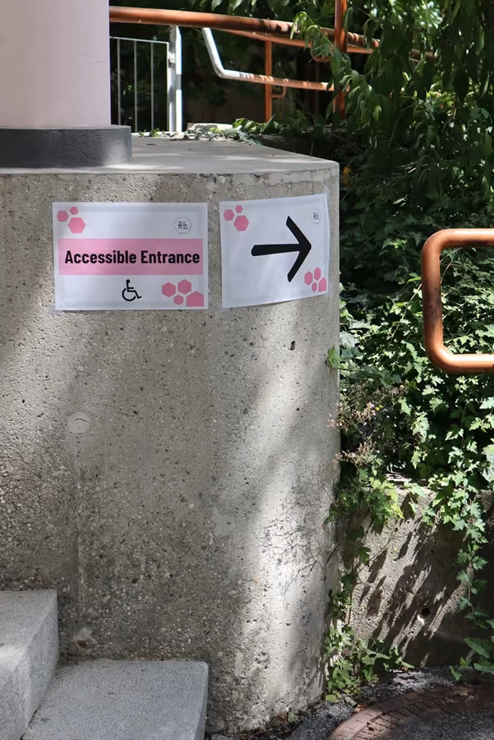 Colourful signs attached to a building wall pointing the way to the accessible entry of the building